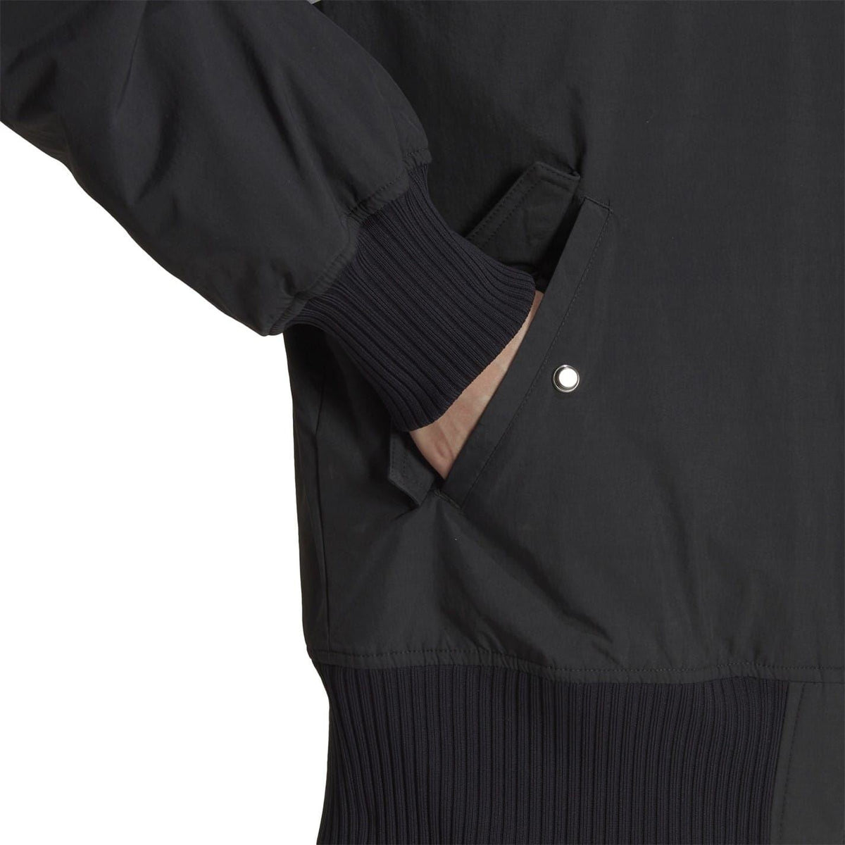 Dark bomber jacket close-up of ribbed cuff and hem with snap button detail.