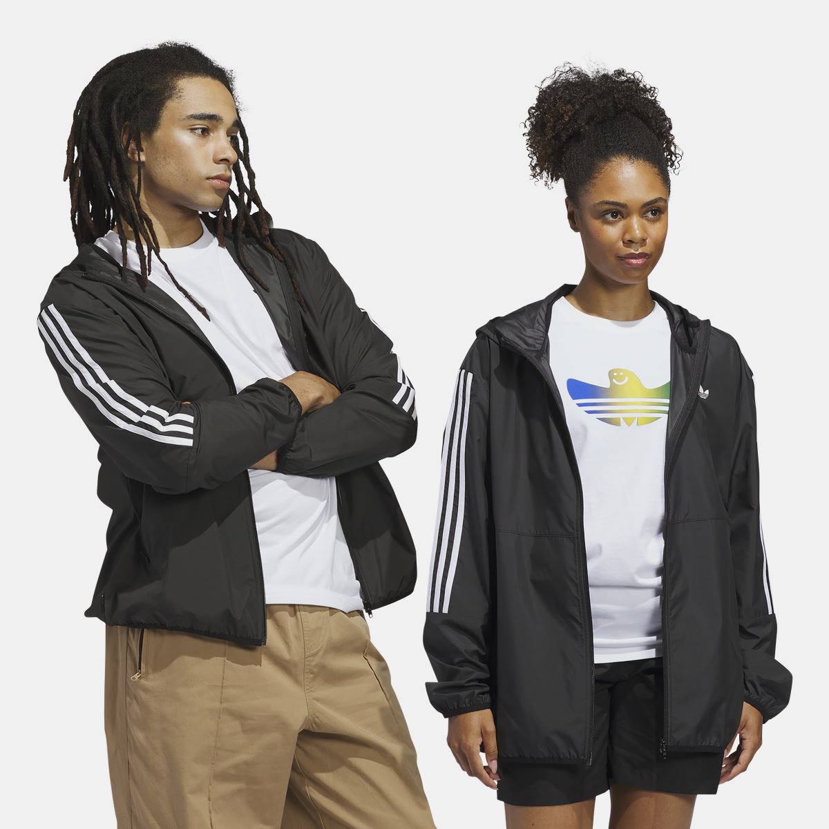 Black hooded windbreaker jacket with white three-stripe sleeves, worn over a graphic tee