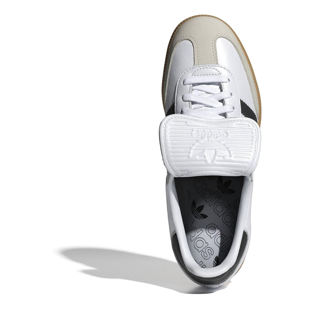 Front view of white lace-up sneakers with black stripe detail and tan outsole trim.