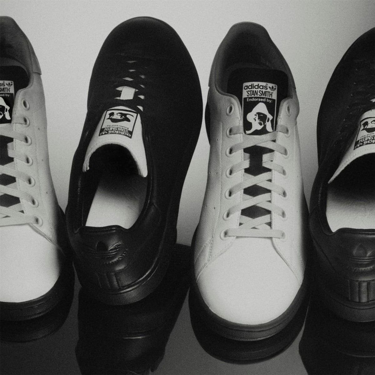 Pair of black and white leather lace-up sneakers with adidas logo tongue labels