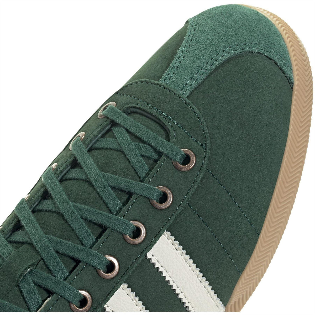 Close-up of green suede low-top sneaker with lace-up eyelets and white stripe