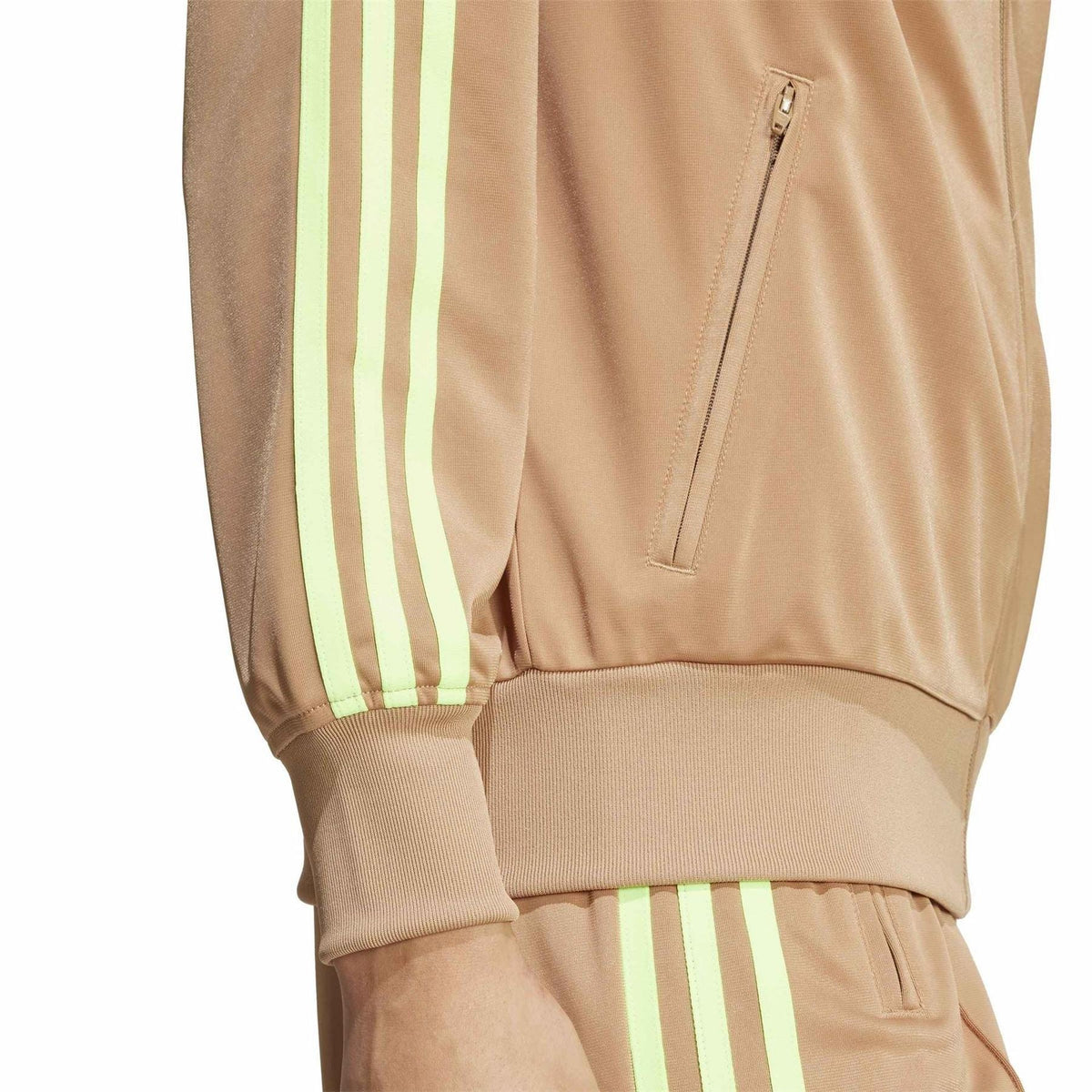 Tan track jacket close-up: front zip, welt pocket, and neon green stripe sleeve detail