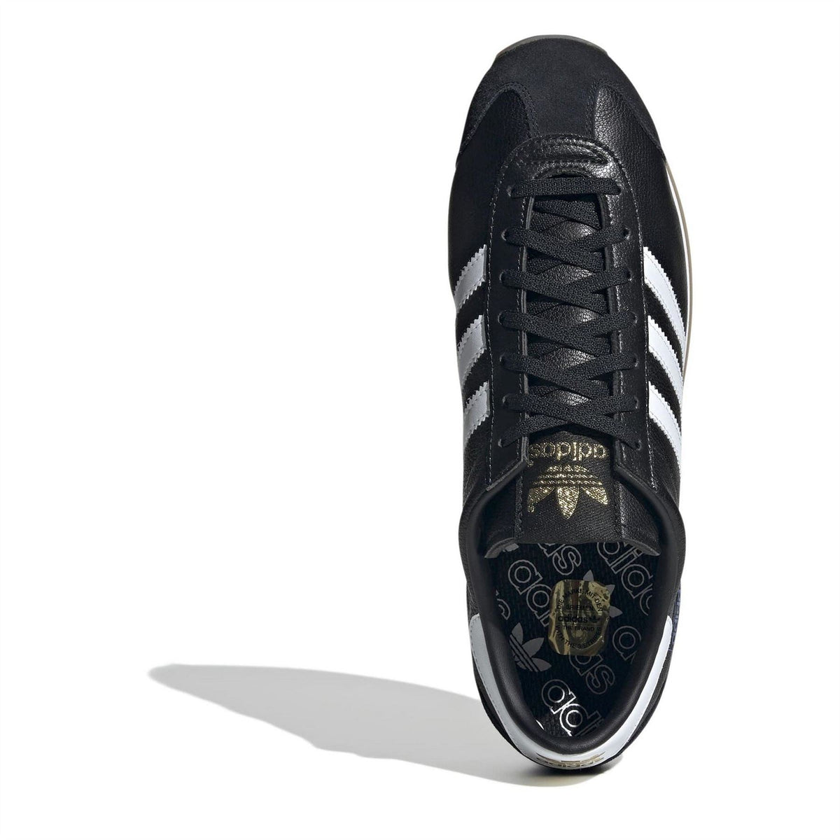 Black lace-up sneakers showing tongue labels, white stripes, and gum sole edge.