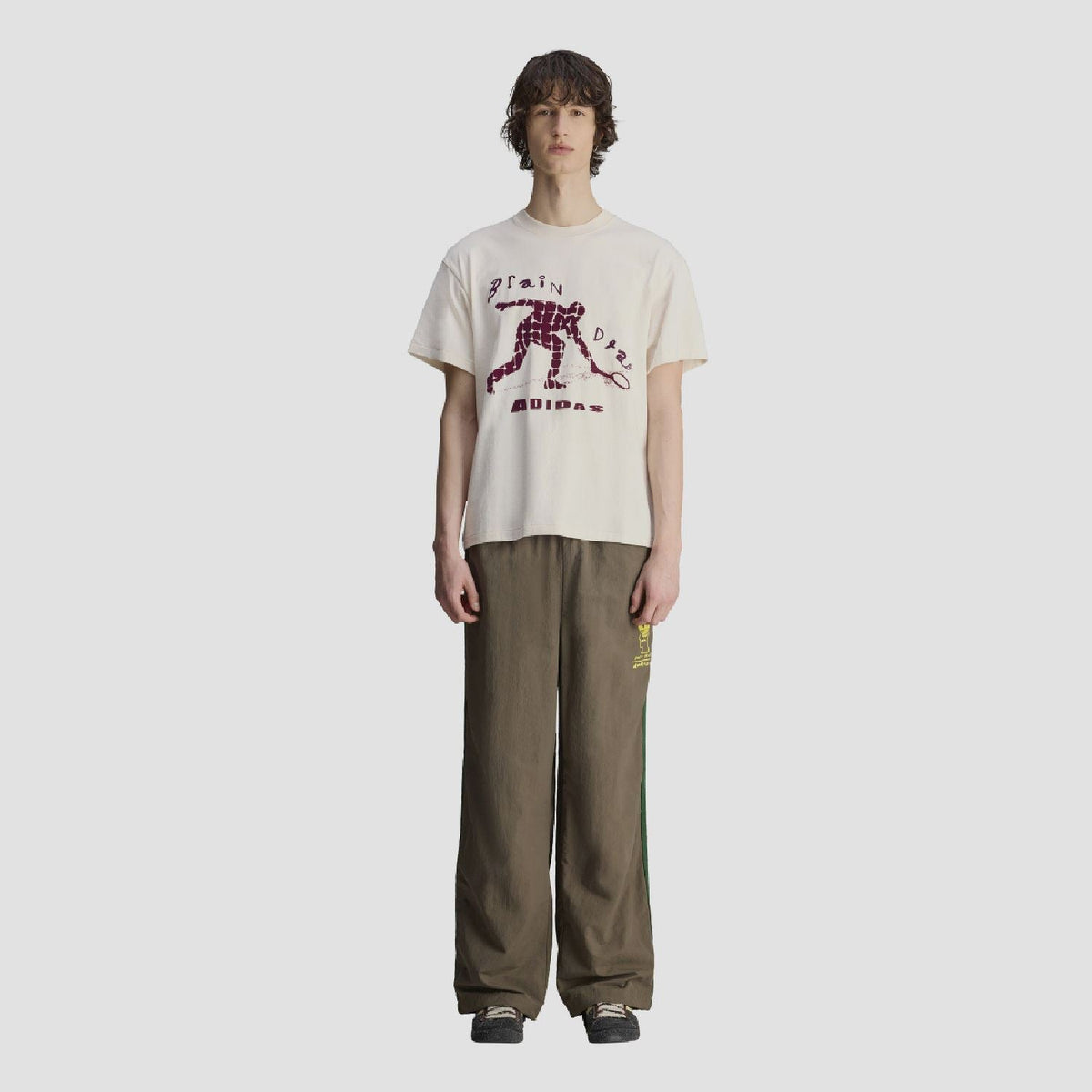 Chocolate wide-leg track pants with elastic cuffs and green side stripes, yellow logo patch