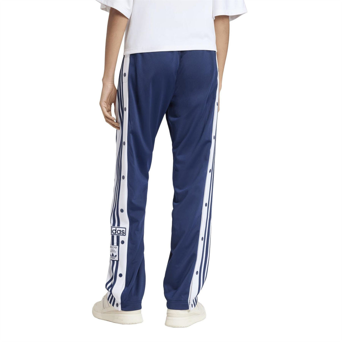 adidas Originals women’s track pants in dark blue with white stripes and ankle-length tapered legs