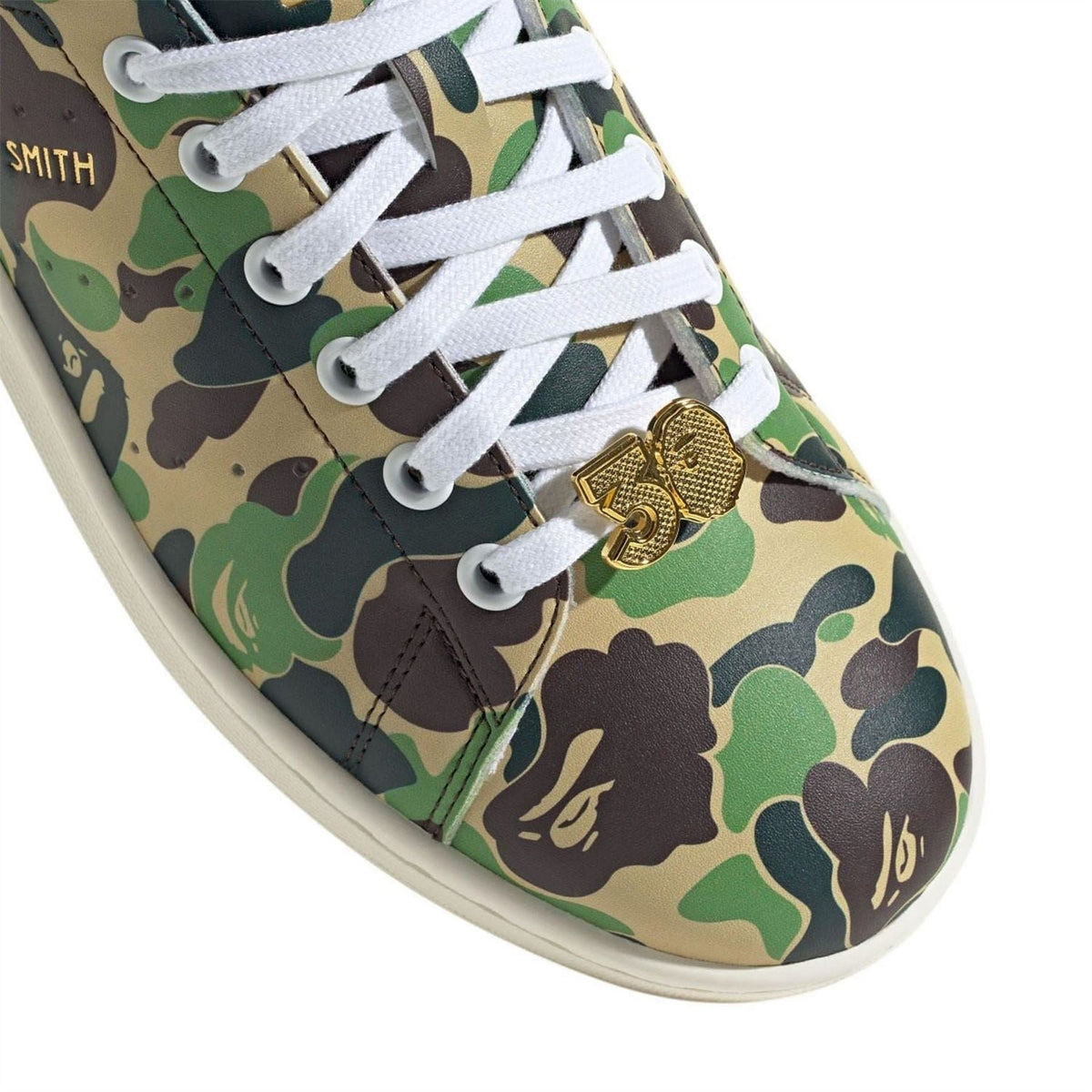 Stan Smith sneaker lace and toe close-up, camo fabric, white laces, gold lace-lock charm
