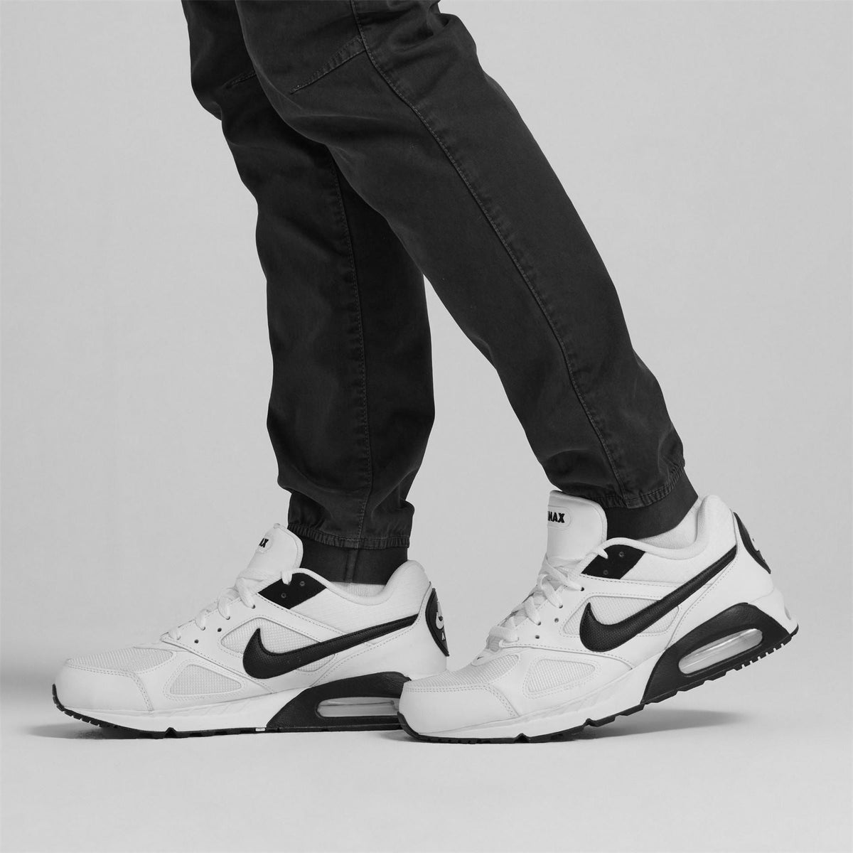 White Nike Air Max Ivo trainers with black swoosh worn with black pants