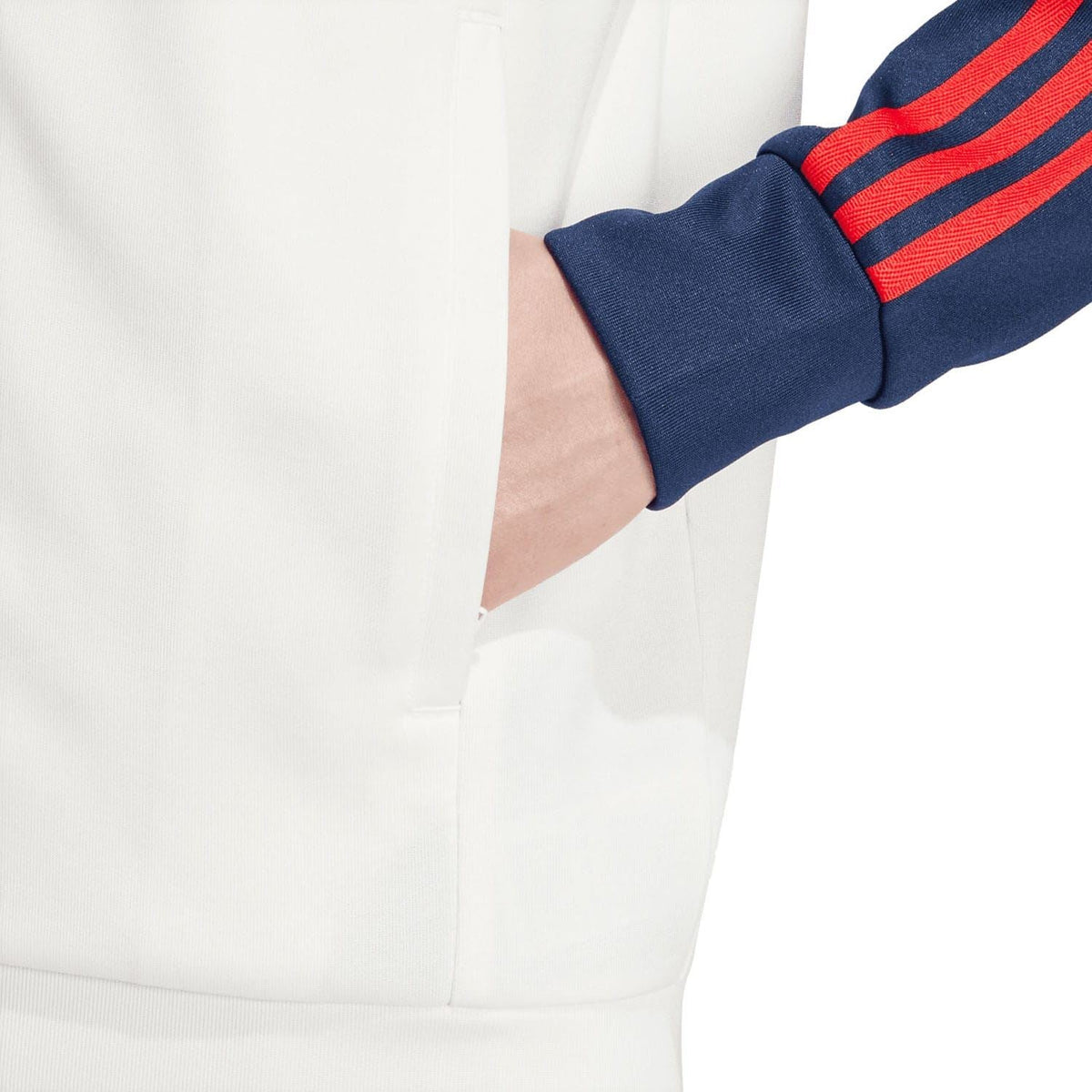 White jacket with navy cuff and red stripe; close-up of front zip and sleeve hem