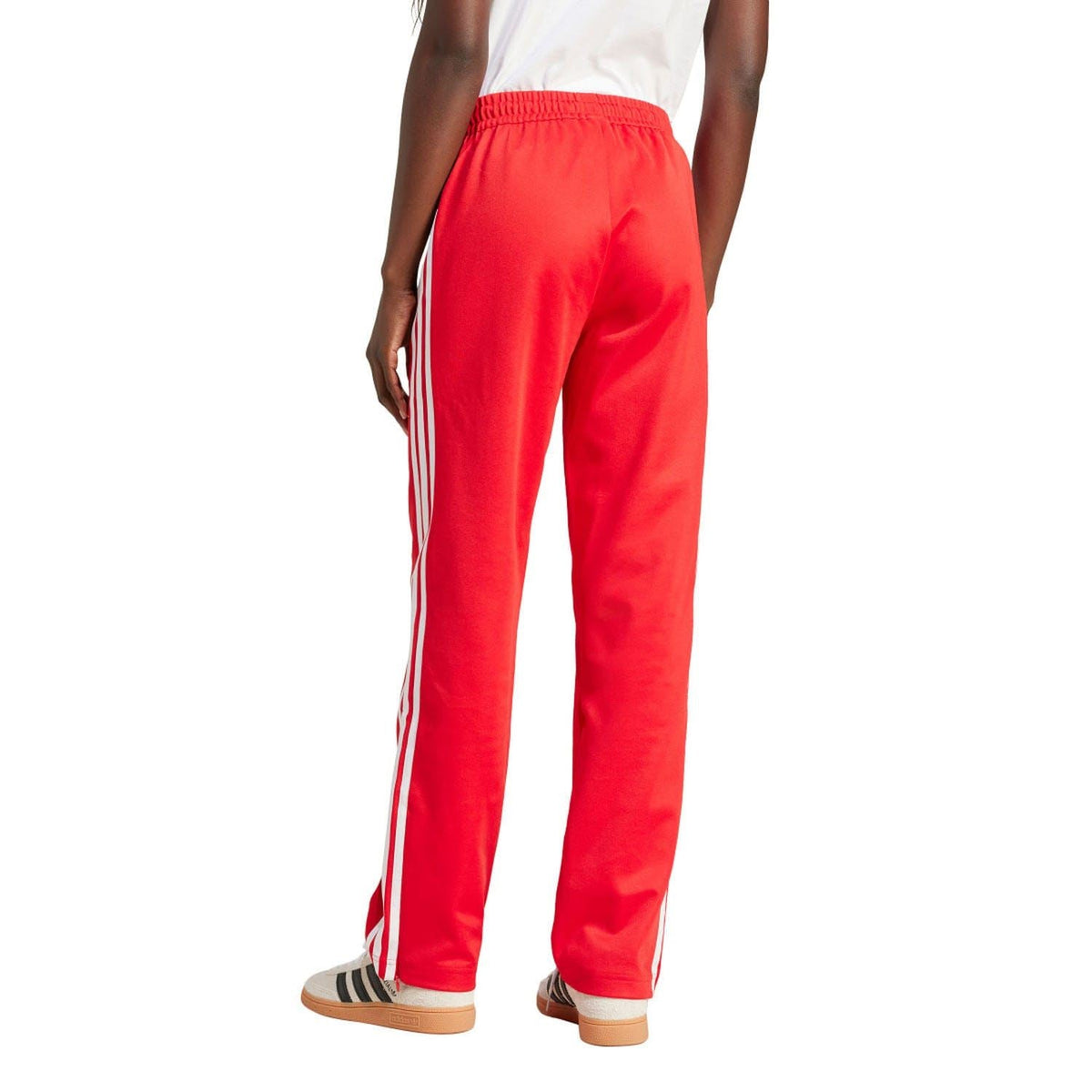 Red adidas track pants with elastic waistband and white side stripes on straight legs.