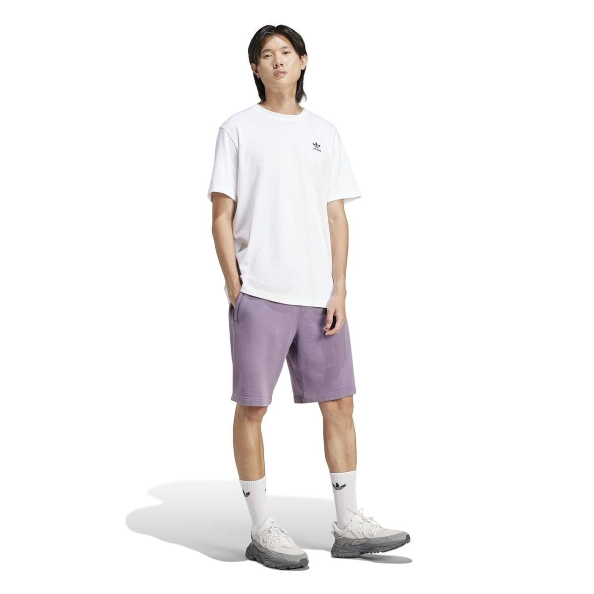Purple adidas bermuda sweat shorts on model, elastic waistband and relaxed silhouette