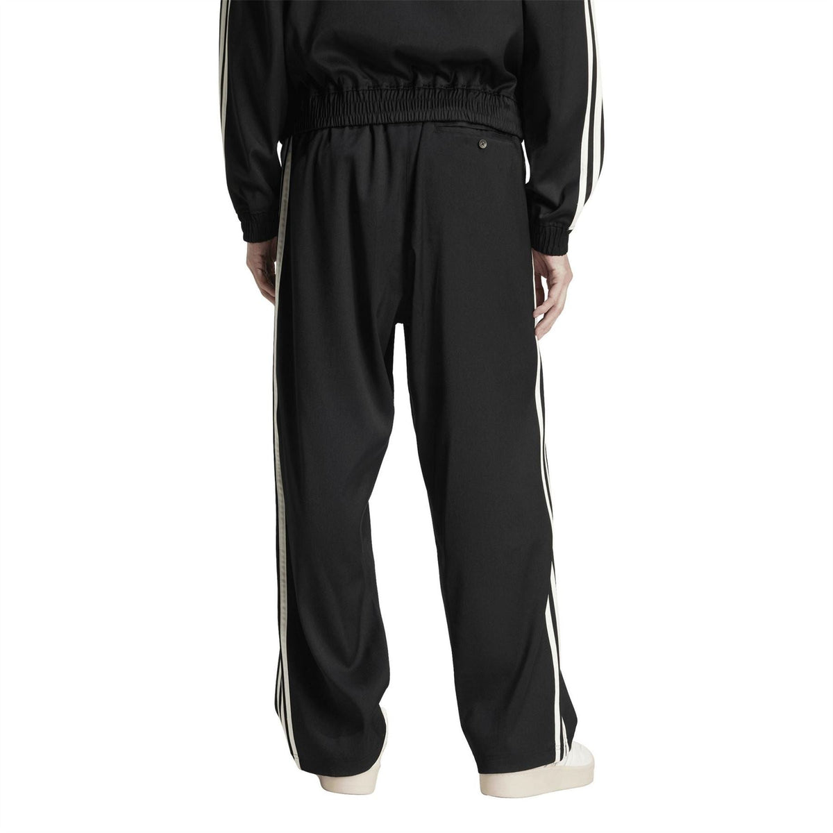 Black adidas baggy track pants with side white stripes and relaxed tapered fit