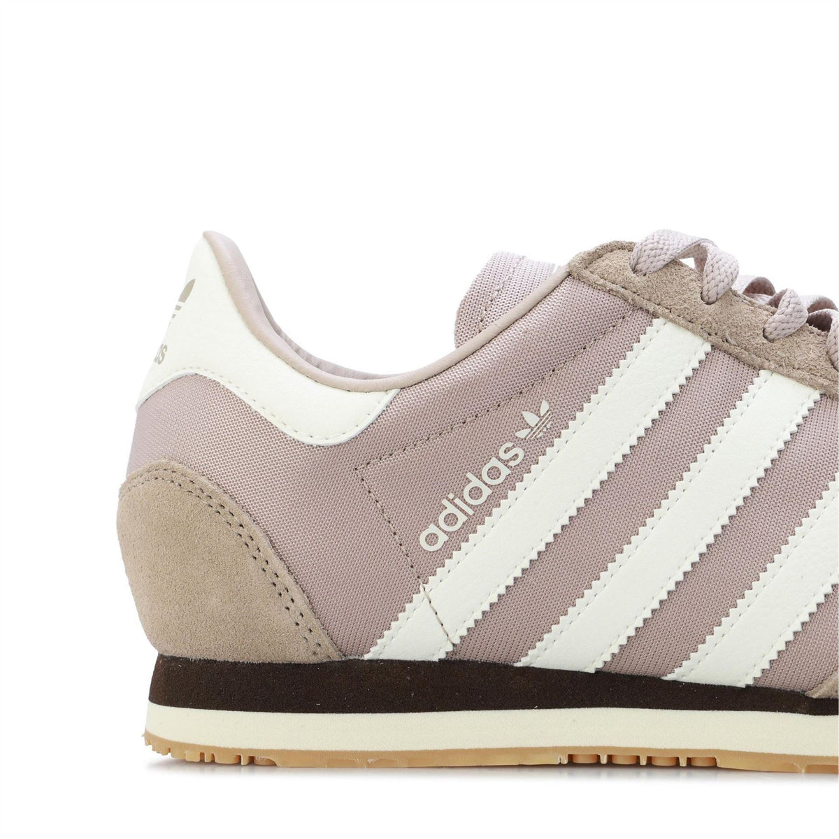 Side close-up of beige adidas trainers with white stripes and lace-up front