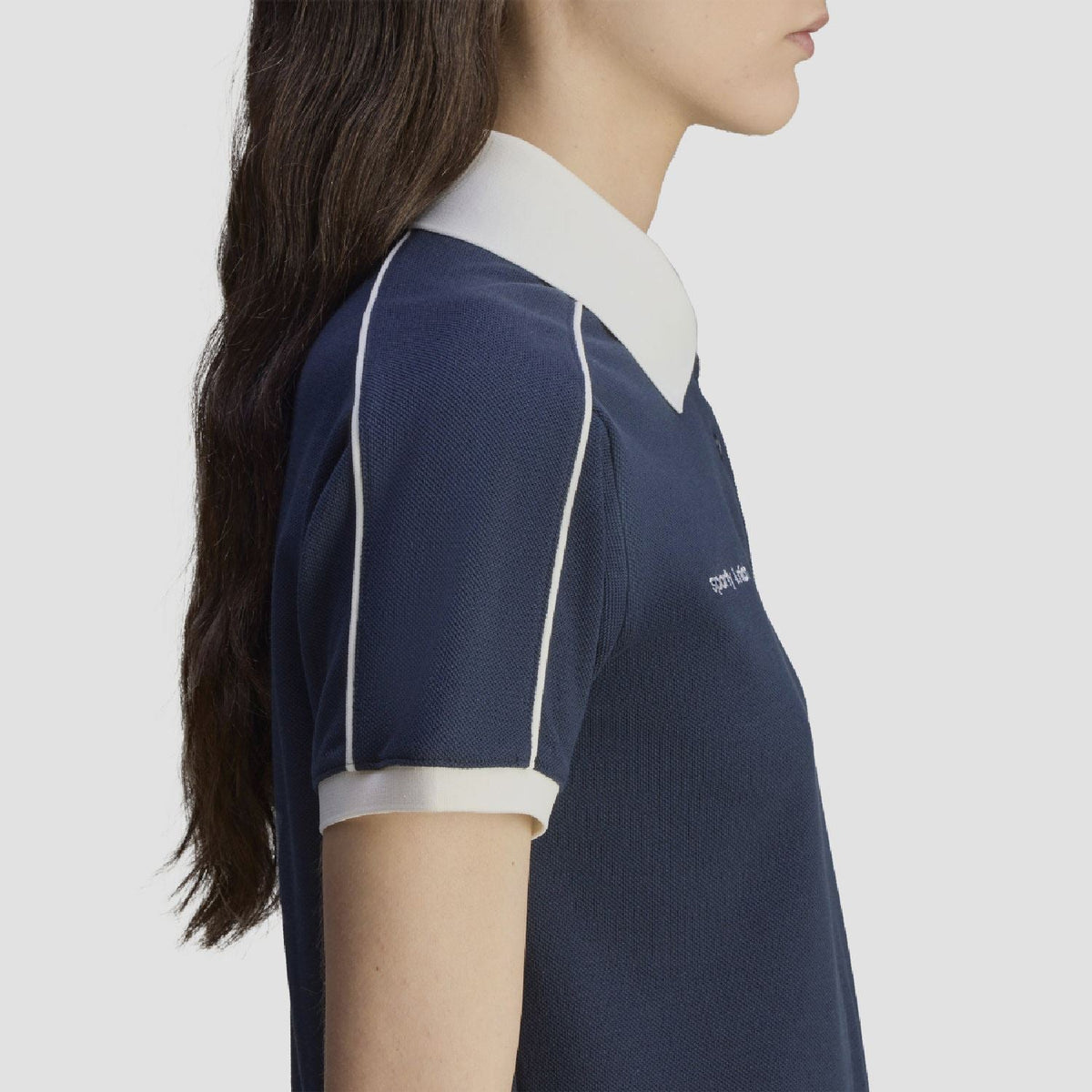 Navy polo shirt sleeve close-up with white contrast stripe detail and white collar
