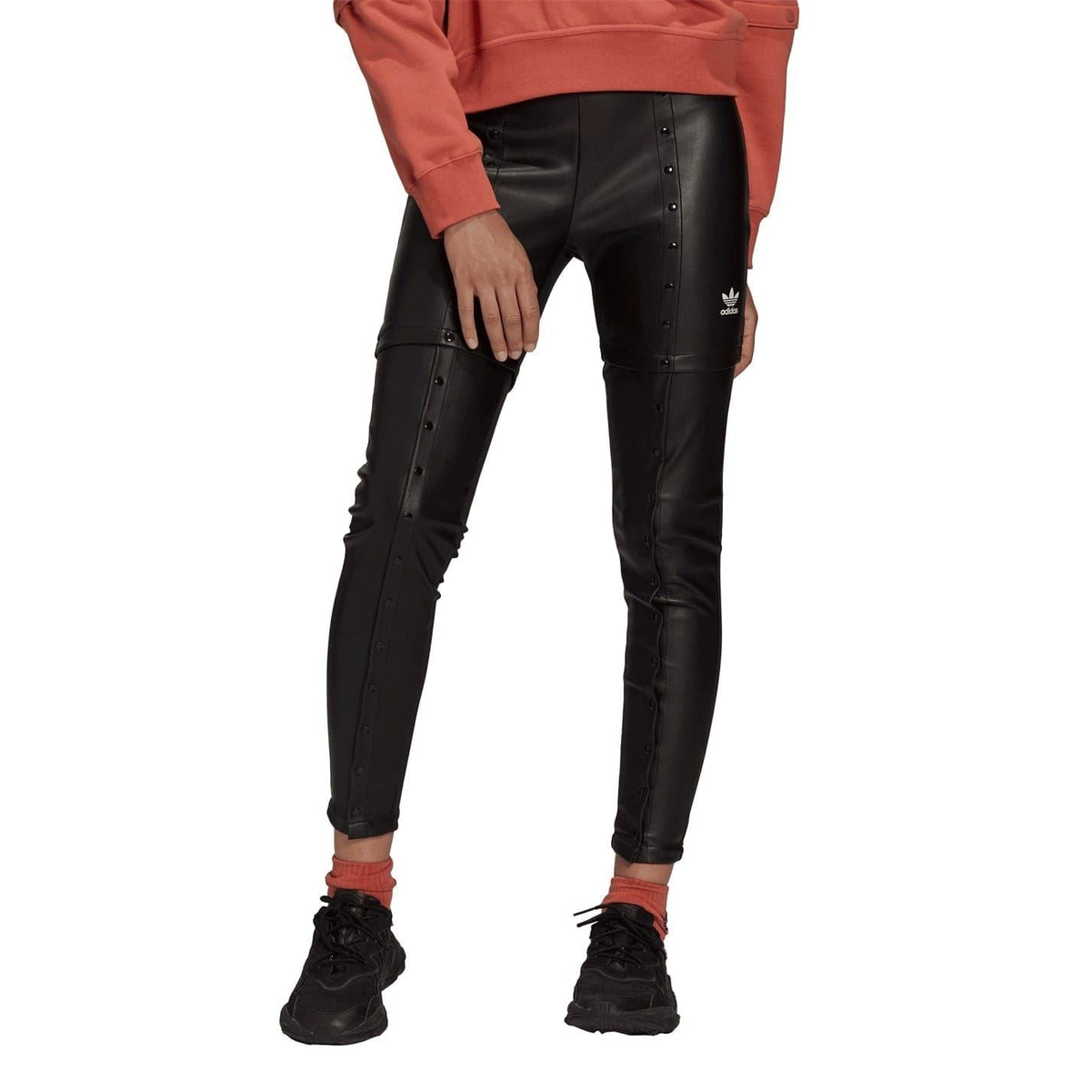 Black faux leather skinny trousers on model, front view with studded button details