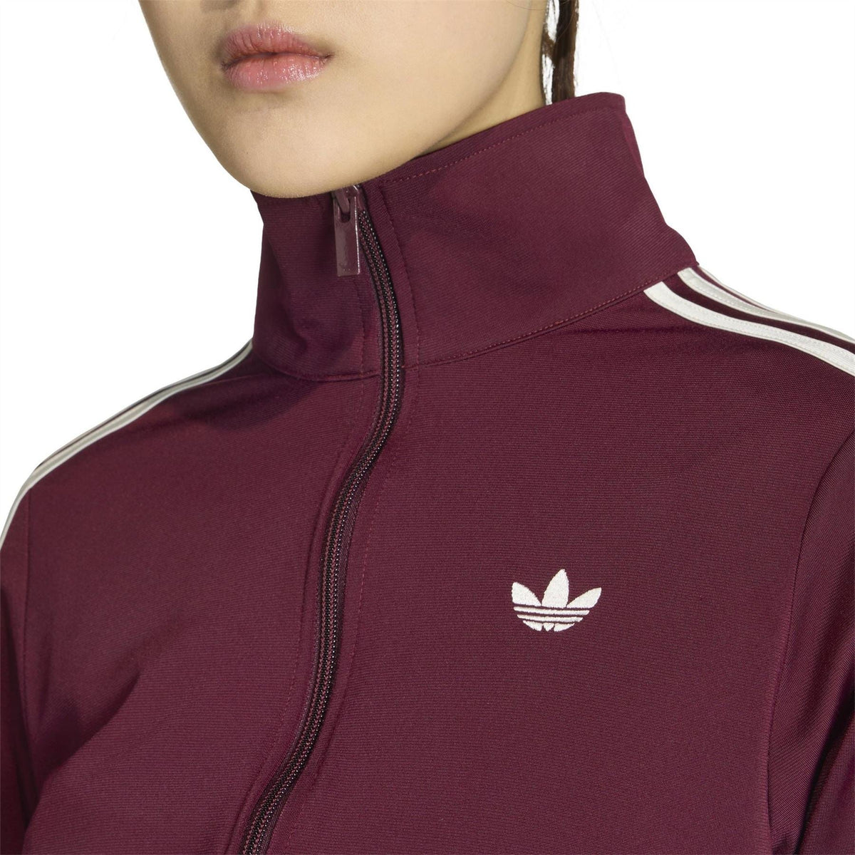 Maroon women’s track jacket close-up: raised collar, zip front, adidas logo on chest.