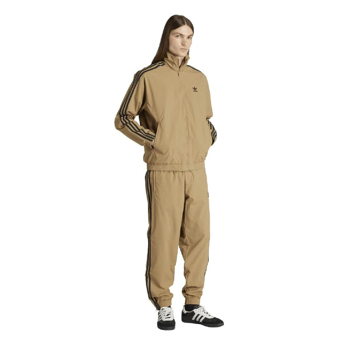 Tan track jacket top with high neck zip and navy stripe details, worn with pants.