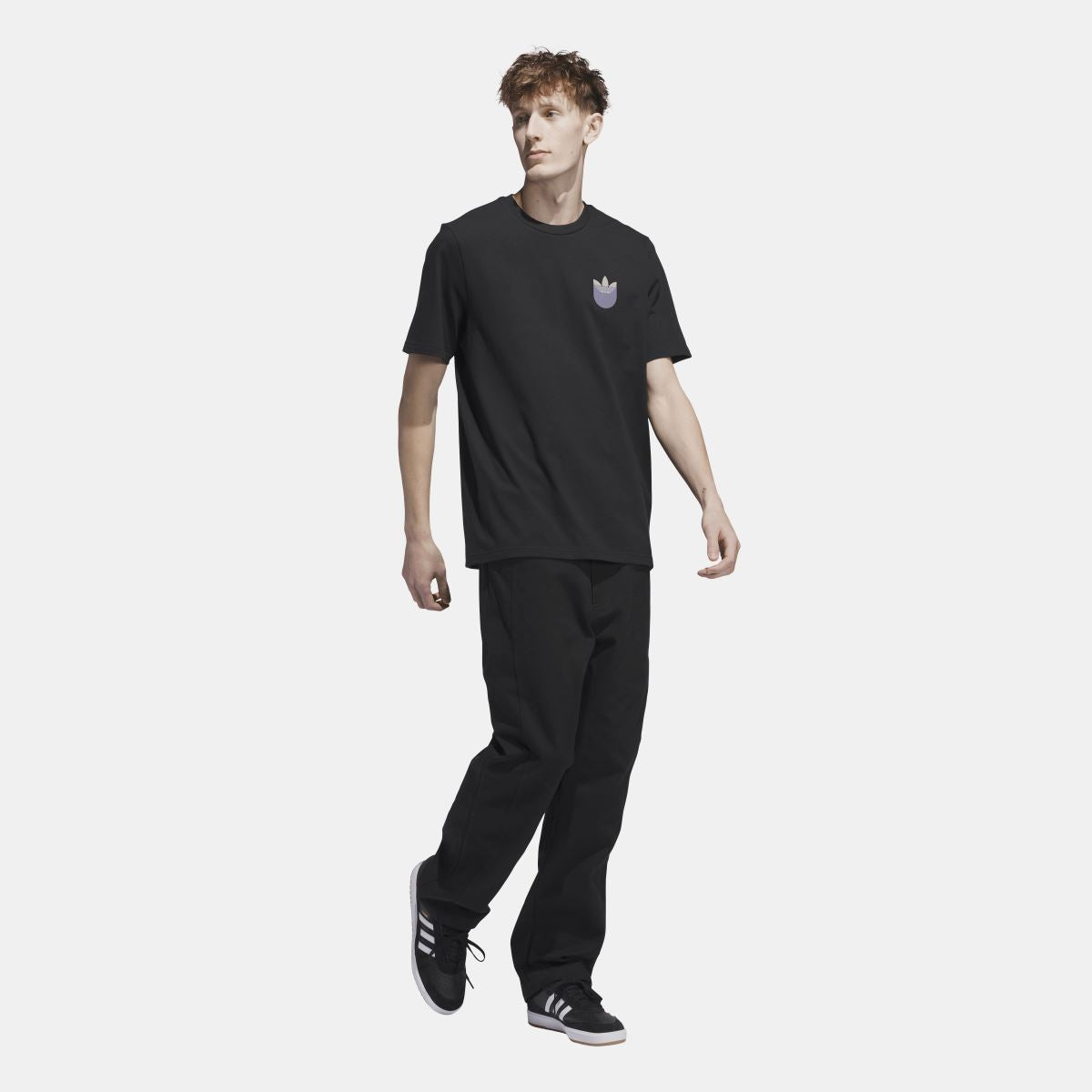 Black short-sleeve t-shirt with chest trefoil shadow logo, styled with pants