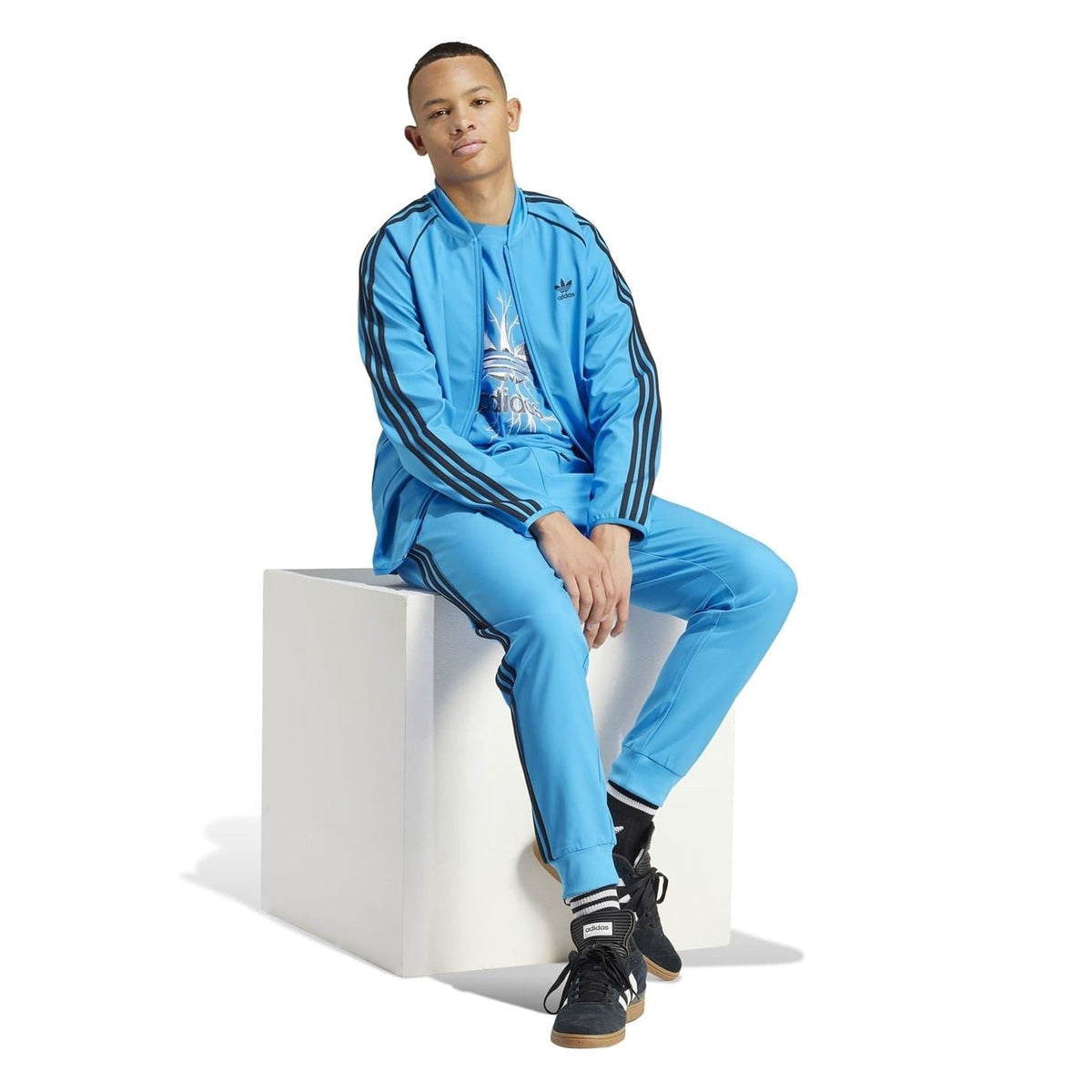 Blue slim track pants worn with track jacket; adidas logo and side stripes