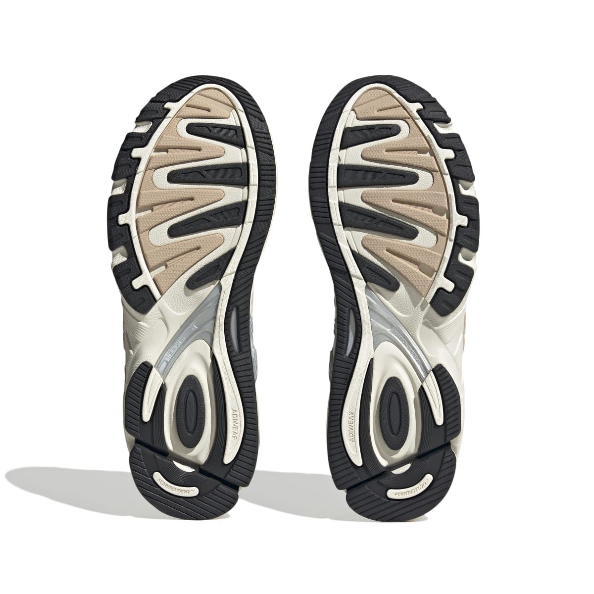 Shoe outsole view with dark tread and off-white midsole on sand upper trainers