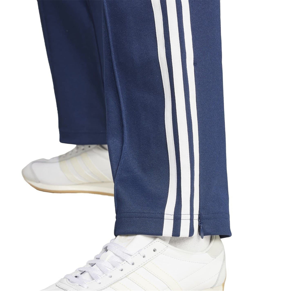 Navy track pants close-up: open hem cuff with three white side stripes