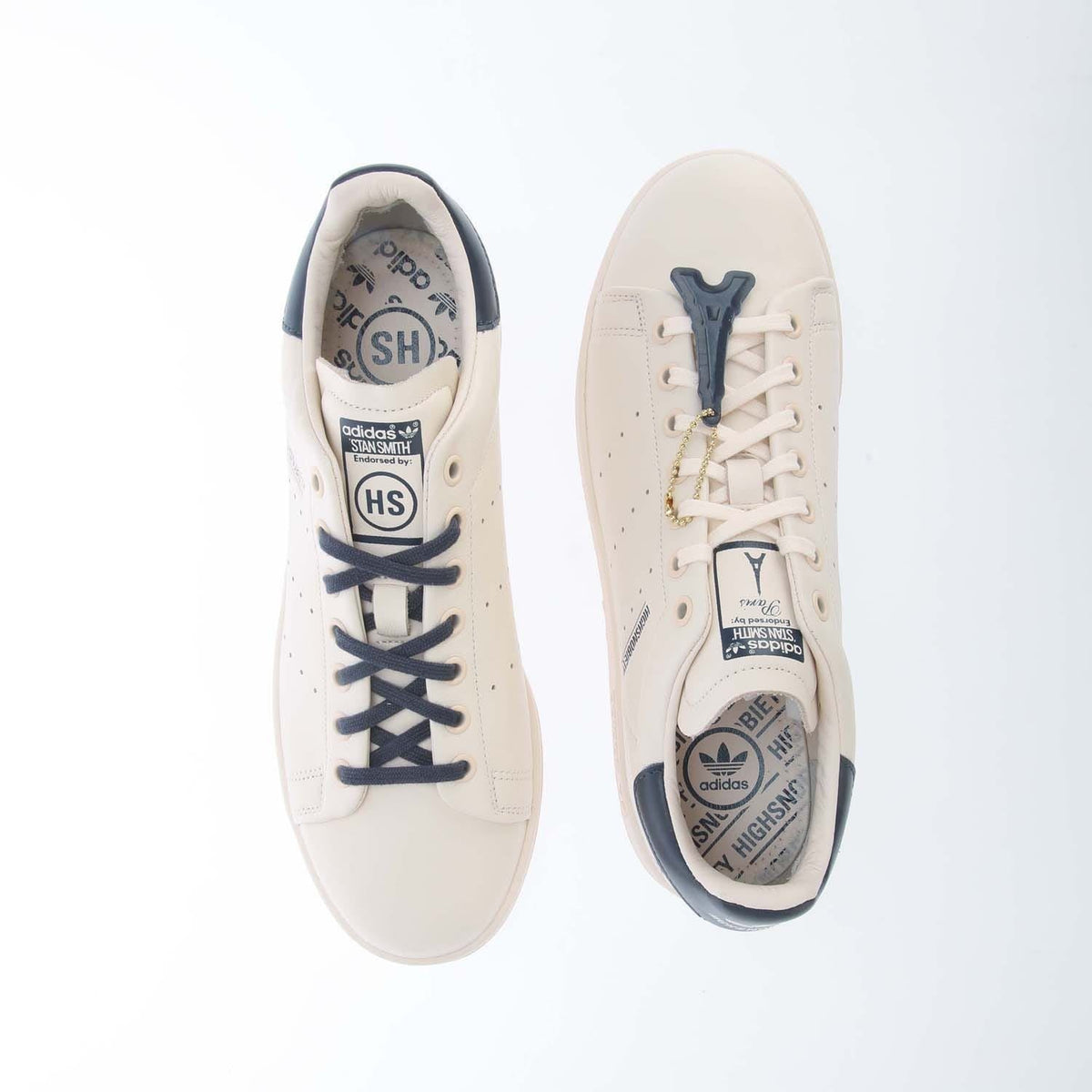Pair of white high-top sneakers with navy laces and visible logo details on the tongue.