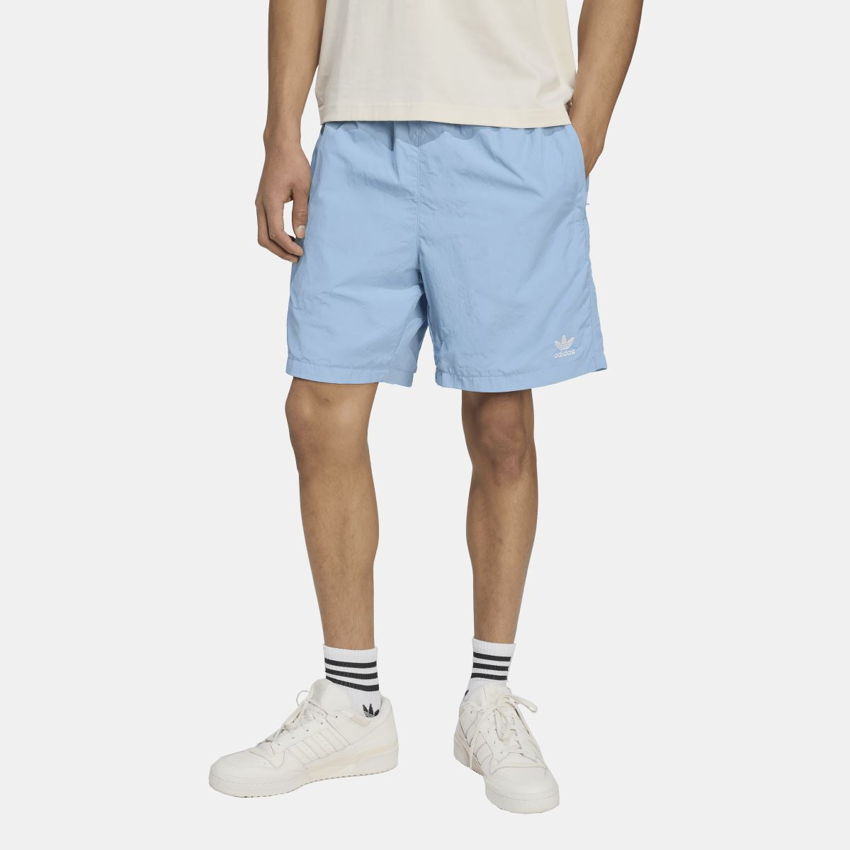 Light blue woven shorts with adidas trefoil logo on hem, model wearing sneakers