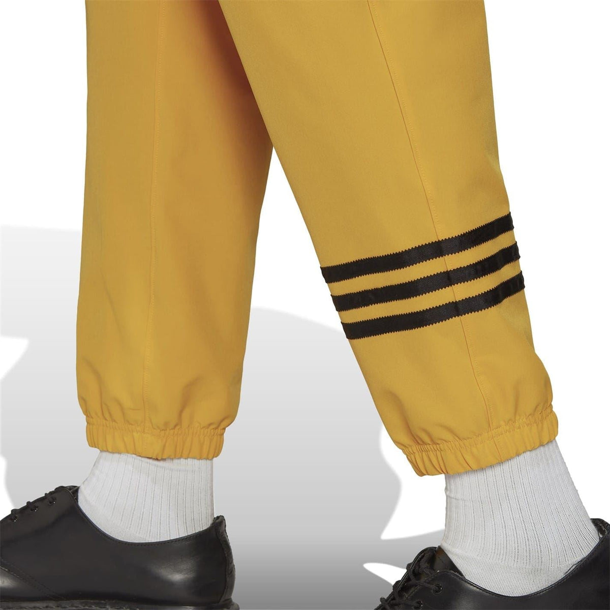 Gold joggers close-up: black-and-navy striped ankle band on ribbed cuff