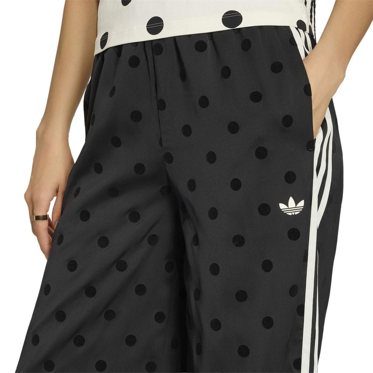 Black polka-dot wide-leg pants with elastic waist and side stripes, close-up