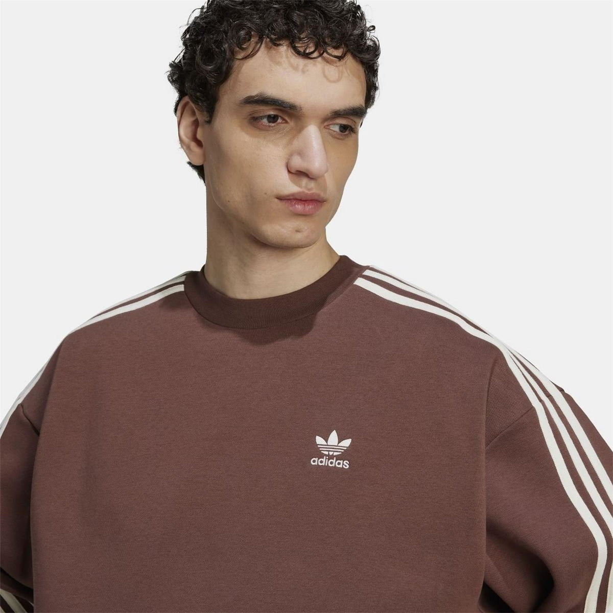 Brown crewneck sweatshirt with adidas trefoil logo on chest and white sleeve stripes