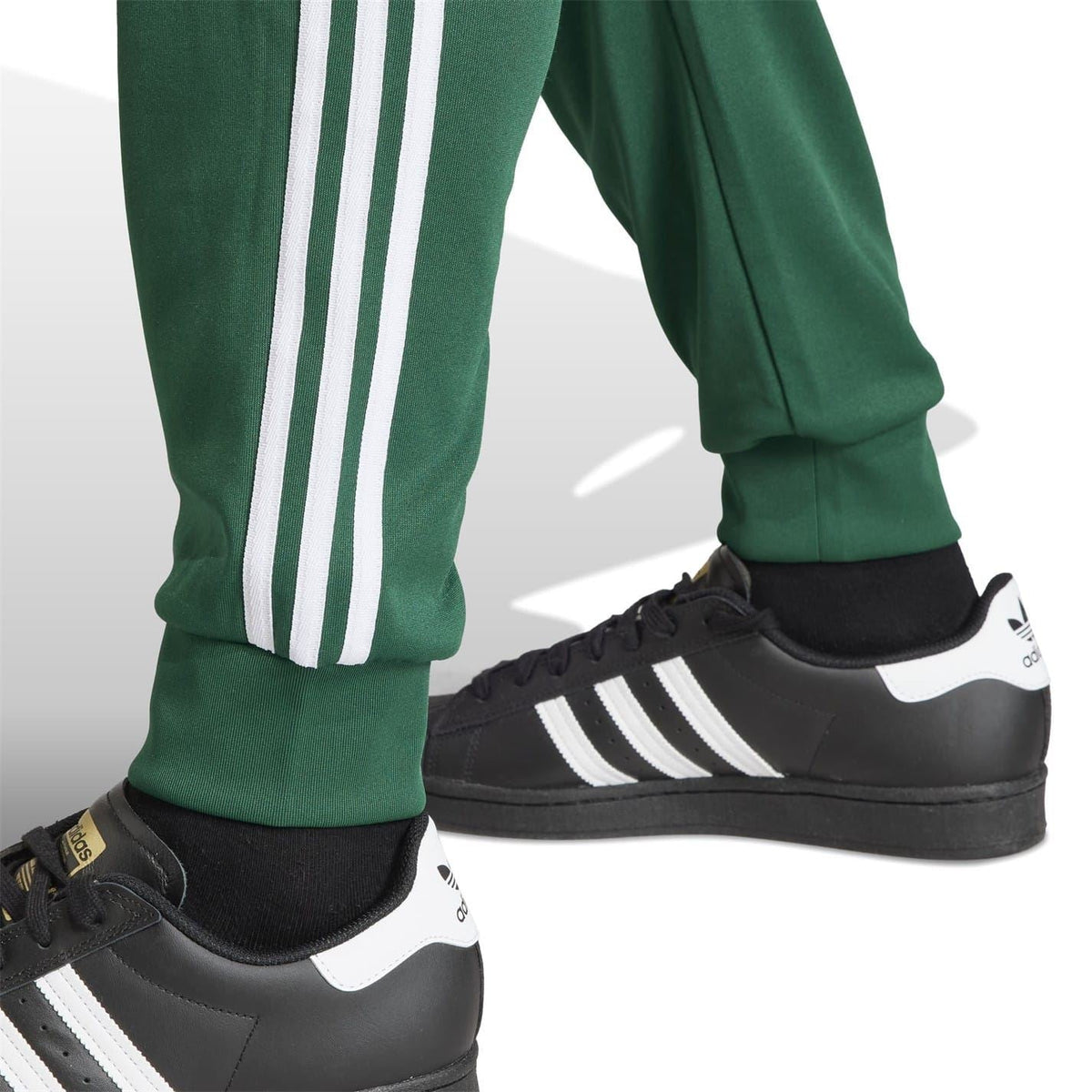 Green slim track pants close-up of white side stripes and tapered cuff