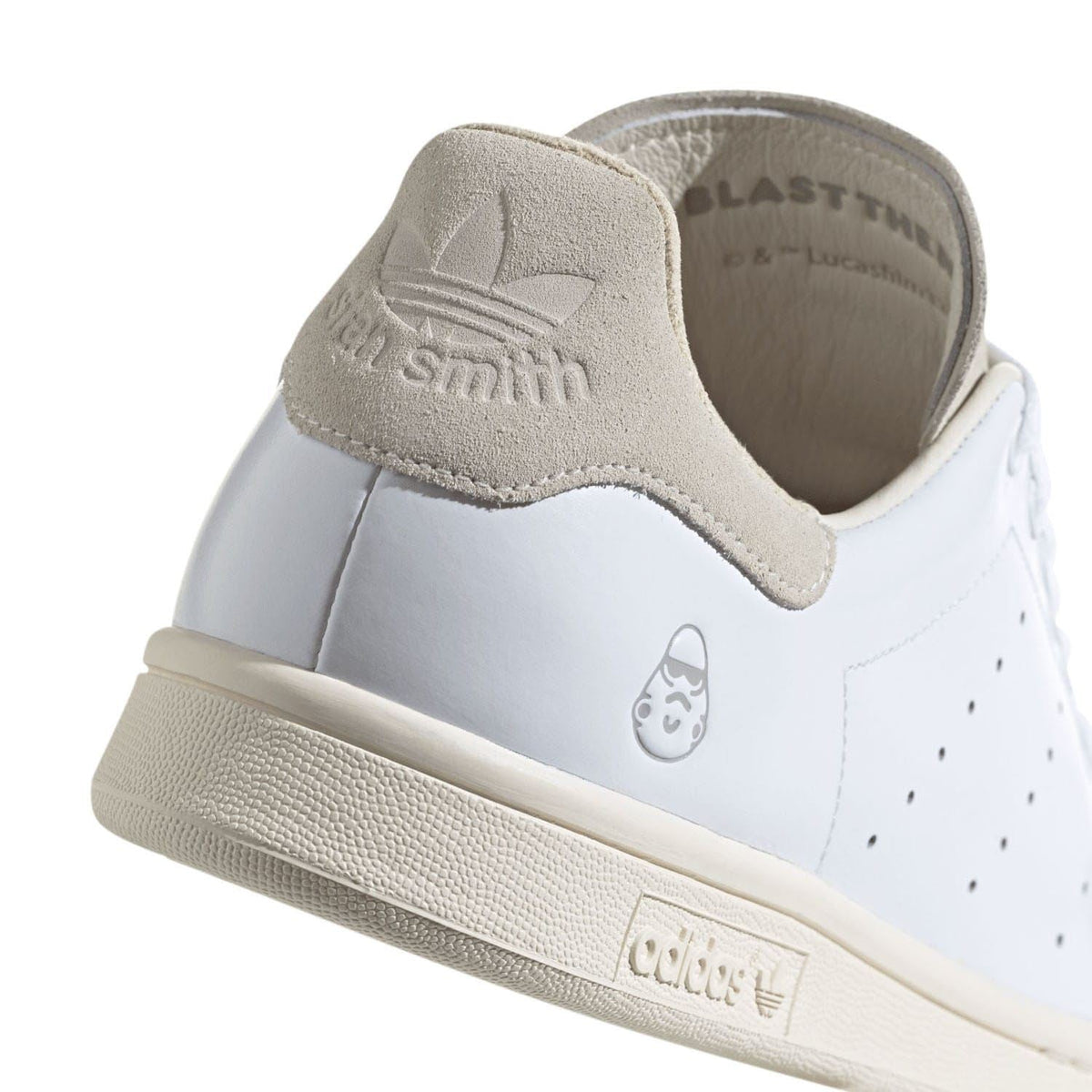 Heel and side view of white trainers with beige suede collar, adidas logo tab