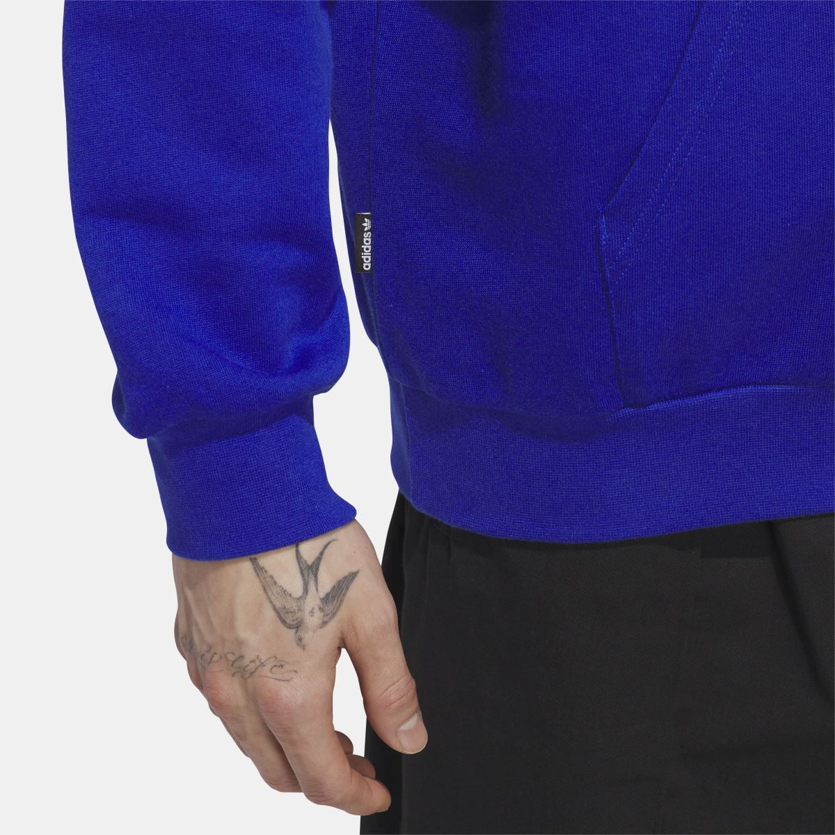 Blue hoodie sleeve and front pocket area with white stripes and drawstring hood strings.