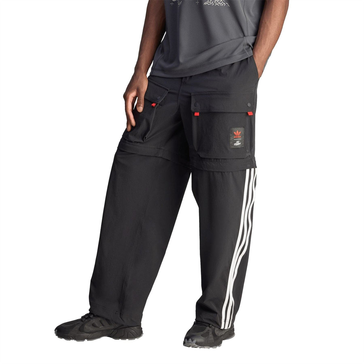 Black jogger pants close-up with cargo pockets, red tabs, and white side stripes