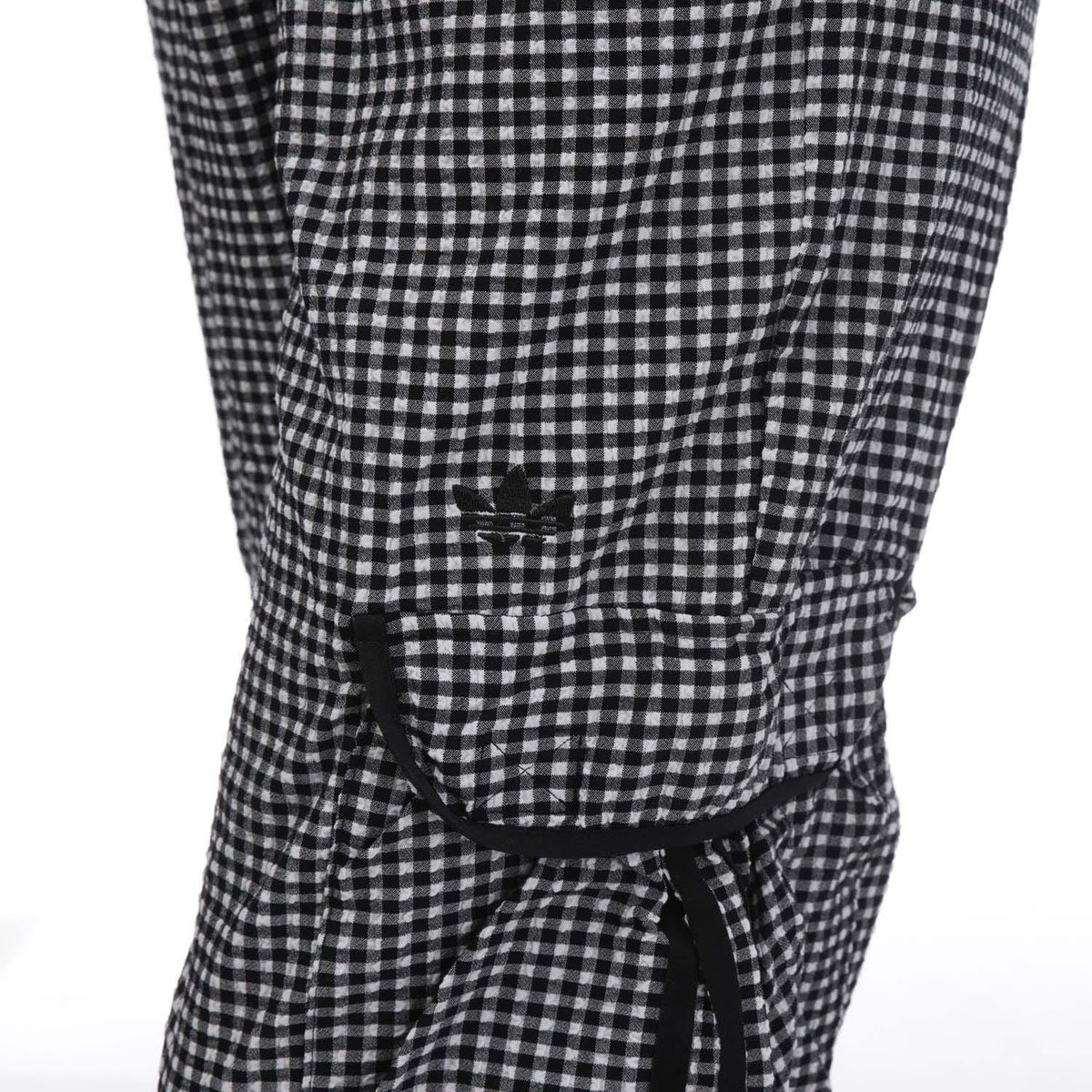 adidas Originals Gingham Track Pants showing the black-and-white checkered design and tapered fit on a model.