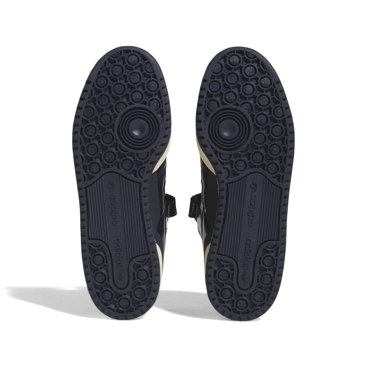 Outsoles of dark navy adidas low-top trainers with circular tread pattern and branding