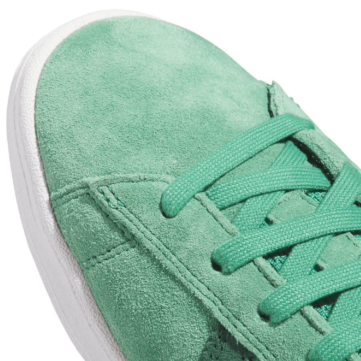 Close-up of green suede trainer with lace-up eyelets and seam stitching