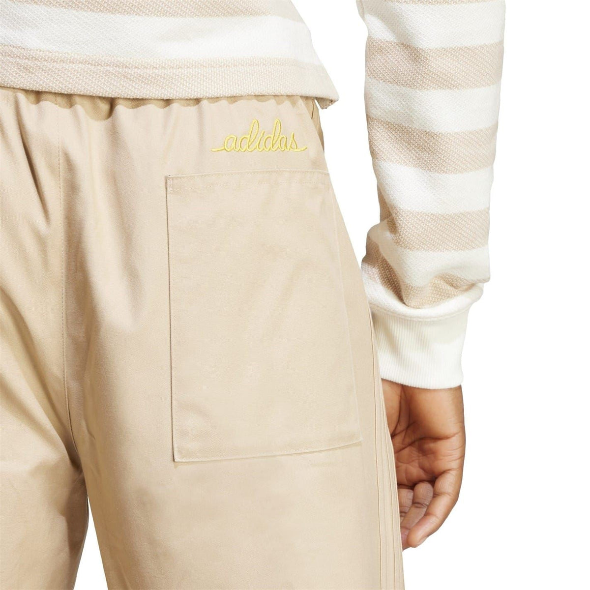Beige drawstring chinos with adidas logo on back pocket and stitched panel