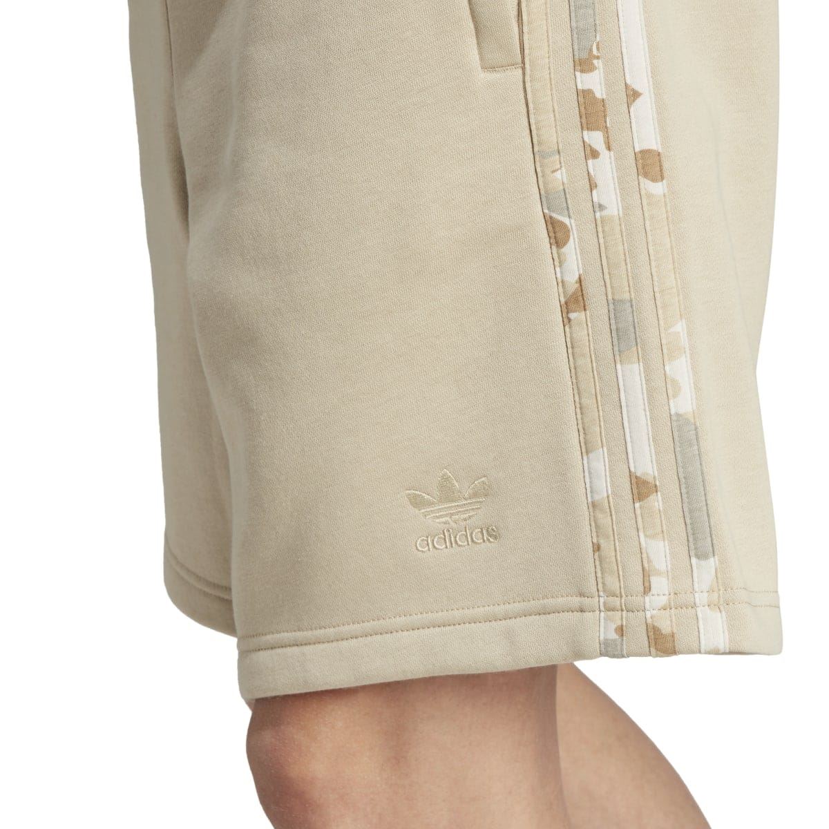 Close-up of sand shorts hem and adidas logo, camo stripe trim along outer seam