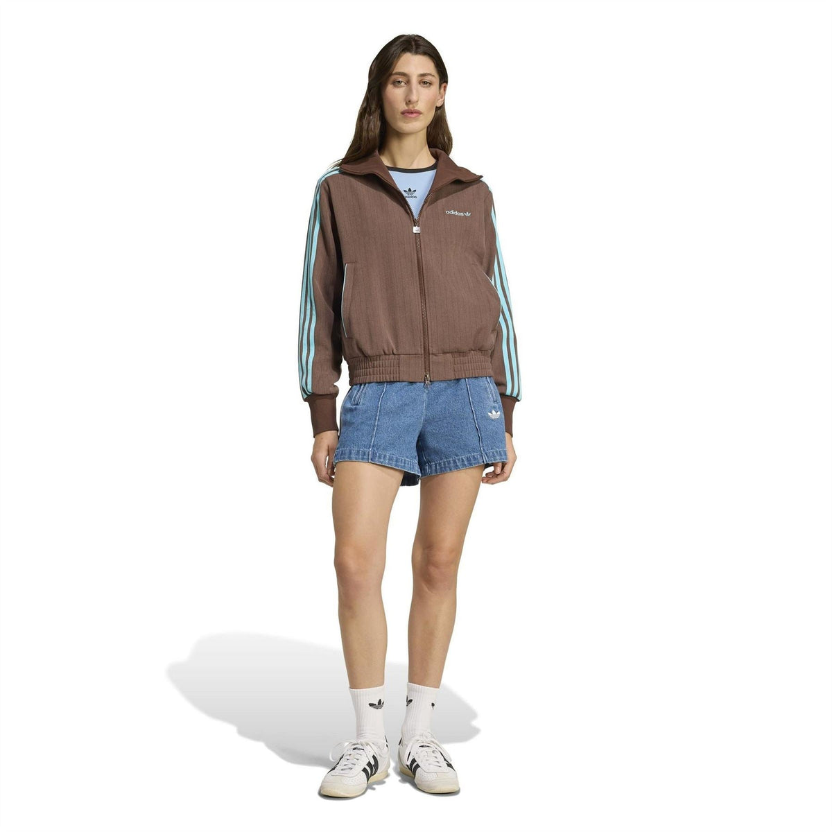 Brown zip-up track jacket with stand collar, turquoise stripes, ribbed cuffs, styled with denim shorts