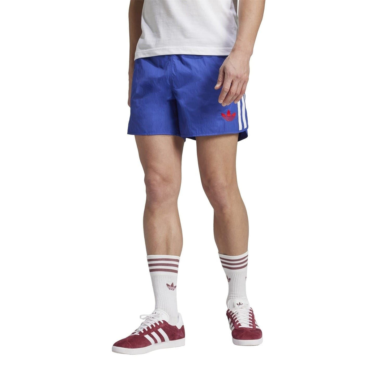 Blue soccer shorts worn by model, elastic waist, white side stripes, red trefoil logo