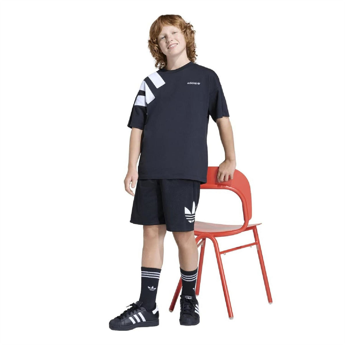 Kids' black shorts with adidas trefoil logo, worn by child with short-sleeve top