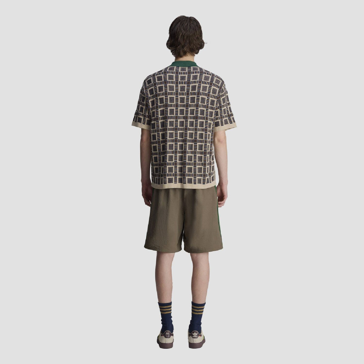 Back view of sand polo shirt with green collar; navy-and-cream geometric grid pattern.