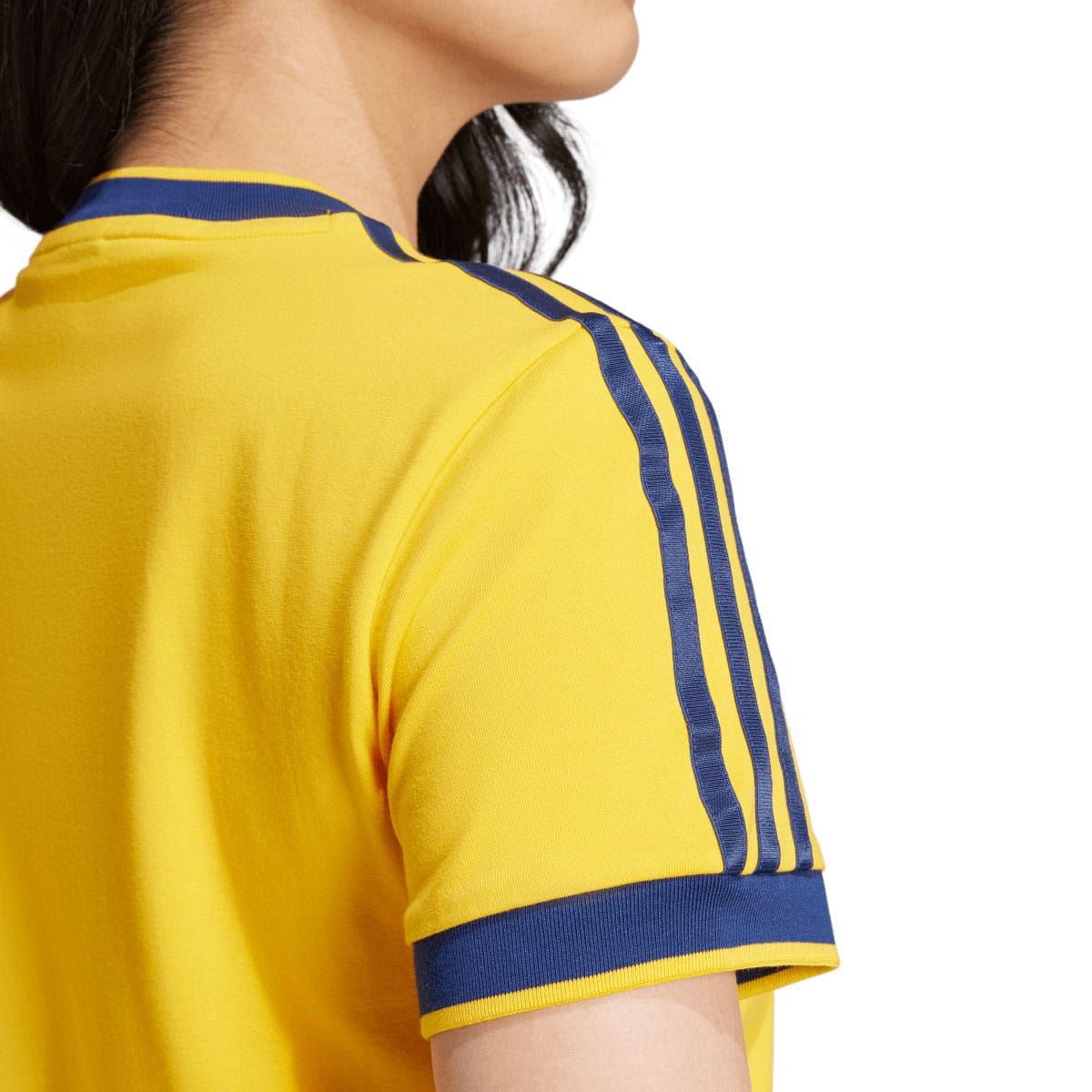 Yellow T-shirt shoulder close-up with blue 3-stripe seam detail and ribbed cuff trim.
