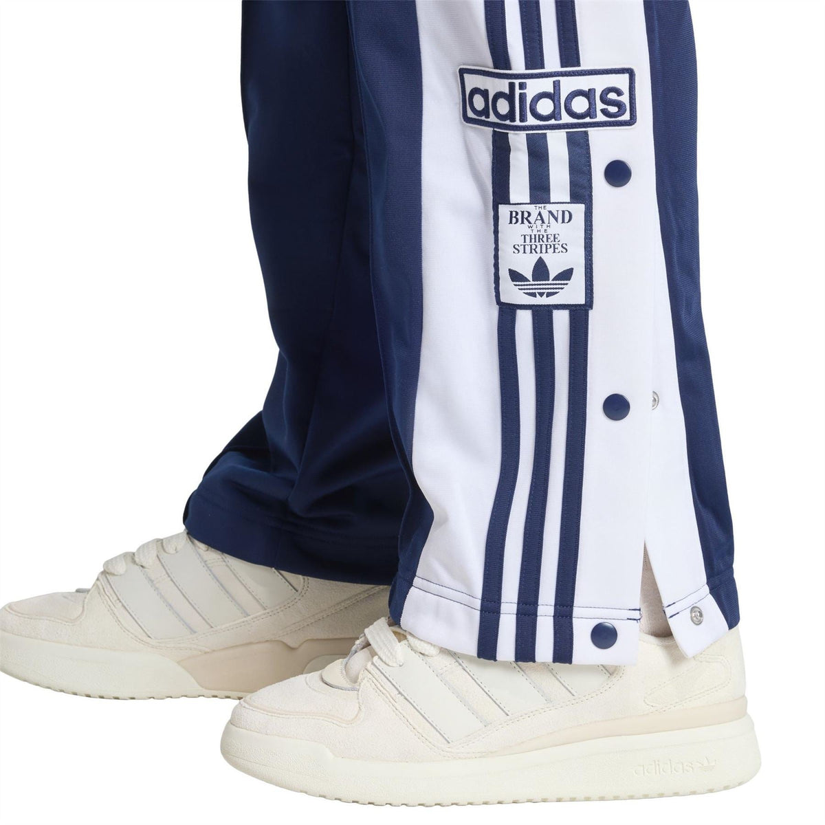 adidas Originals track pants with dark blue fabric and white stripe panel near the hem and adidas logo