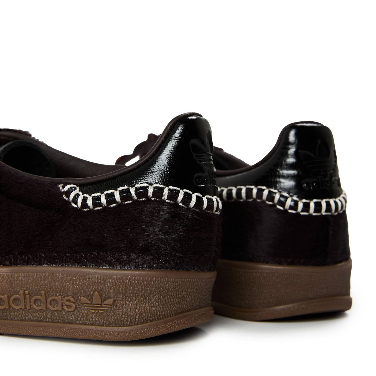 Close-up of black pony Gazelle heel with chain trim, embossed logo on side, gum sole.