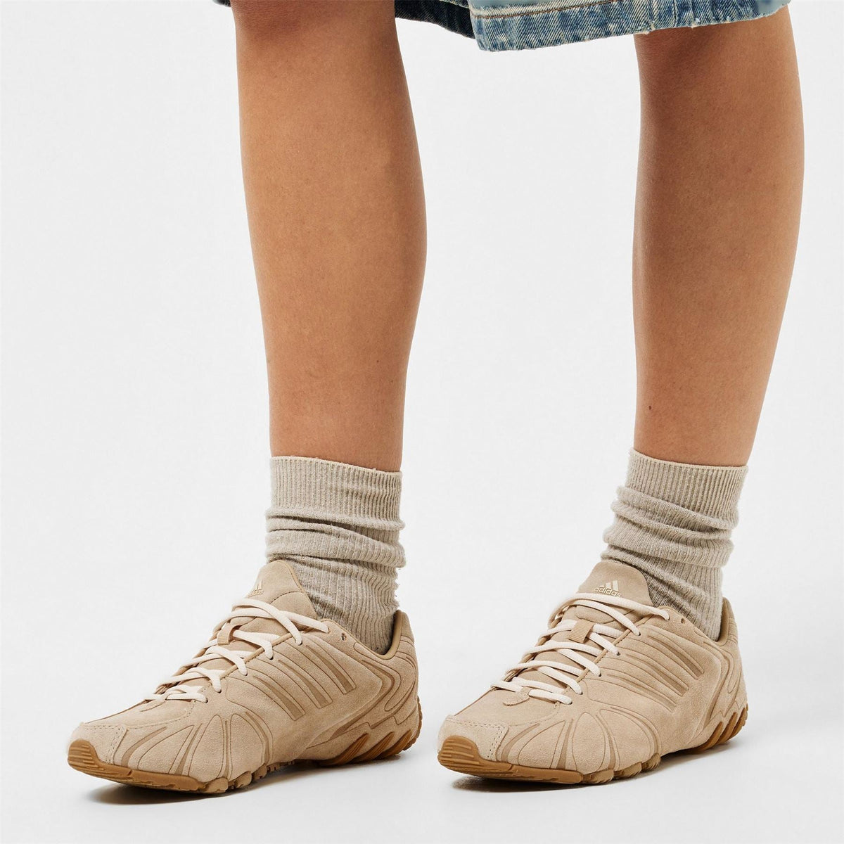 Beige lace-up running shoes worn with crew socks and light denim