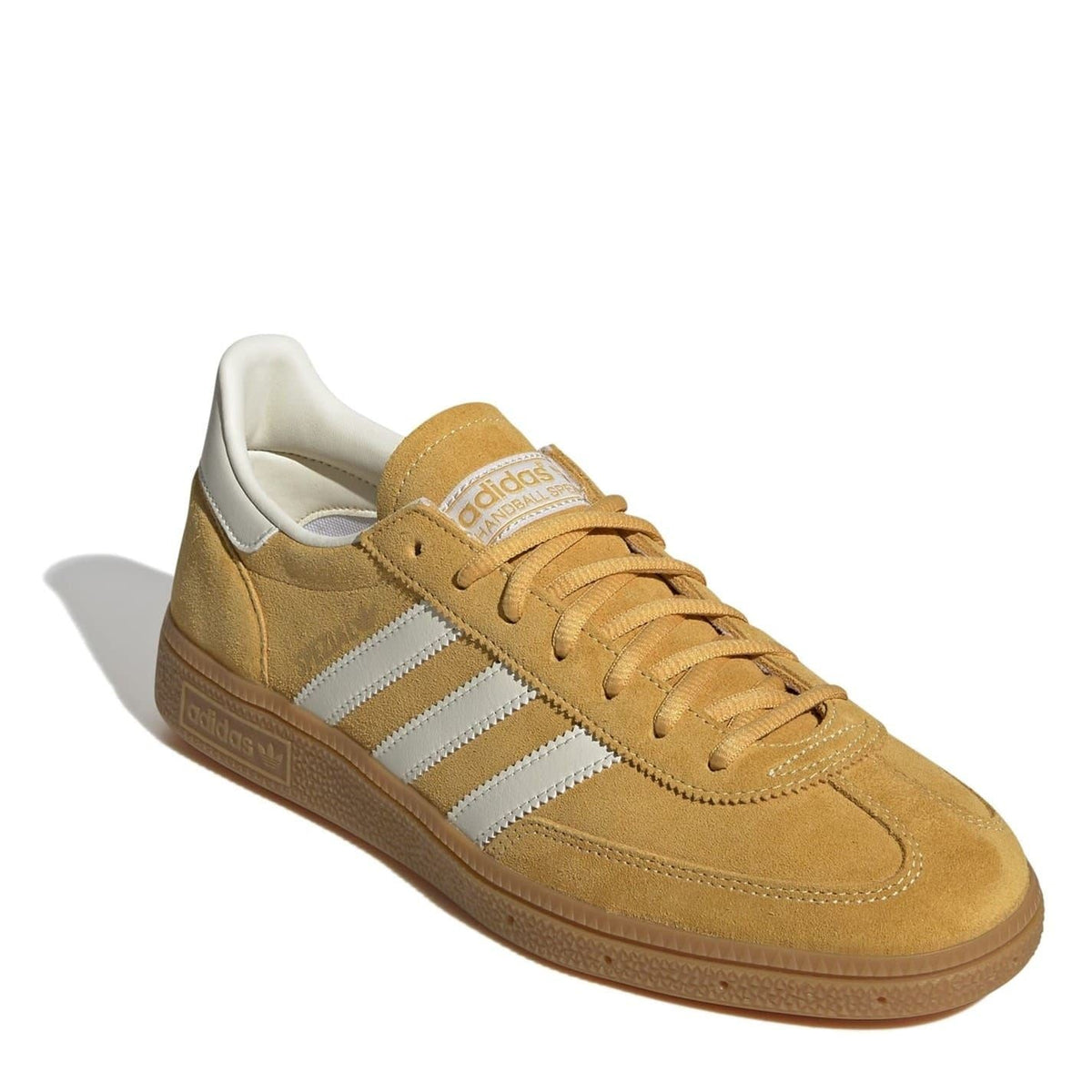 Tan suede low top sneakers in diagonal side view with white stripes and tan laces.