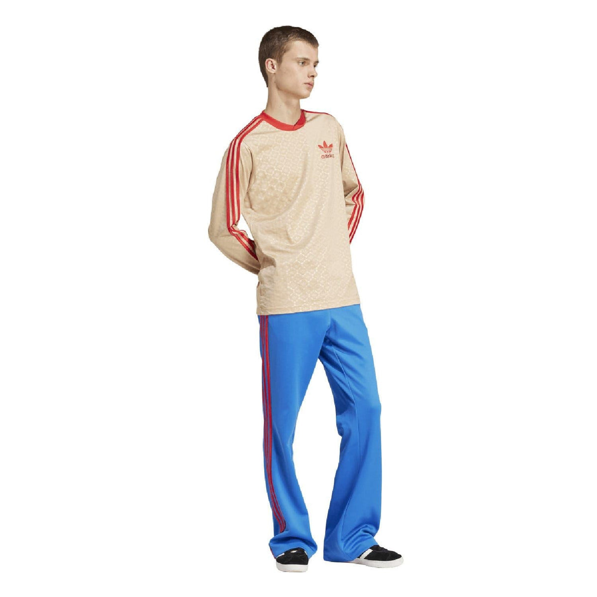 Beige adidas Originals jersey with red sleeve stripes and crew neck, paired with blue pants