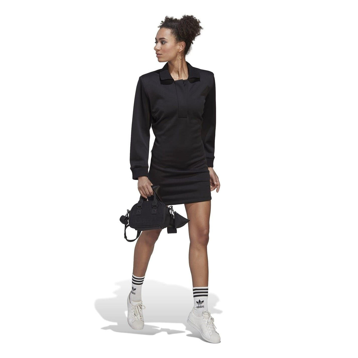 Black long-sleeve mini polo dress on model, standing pose with front button placket.
