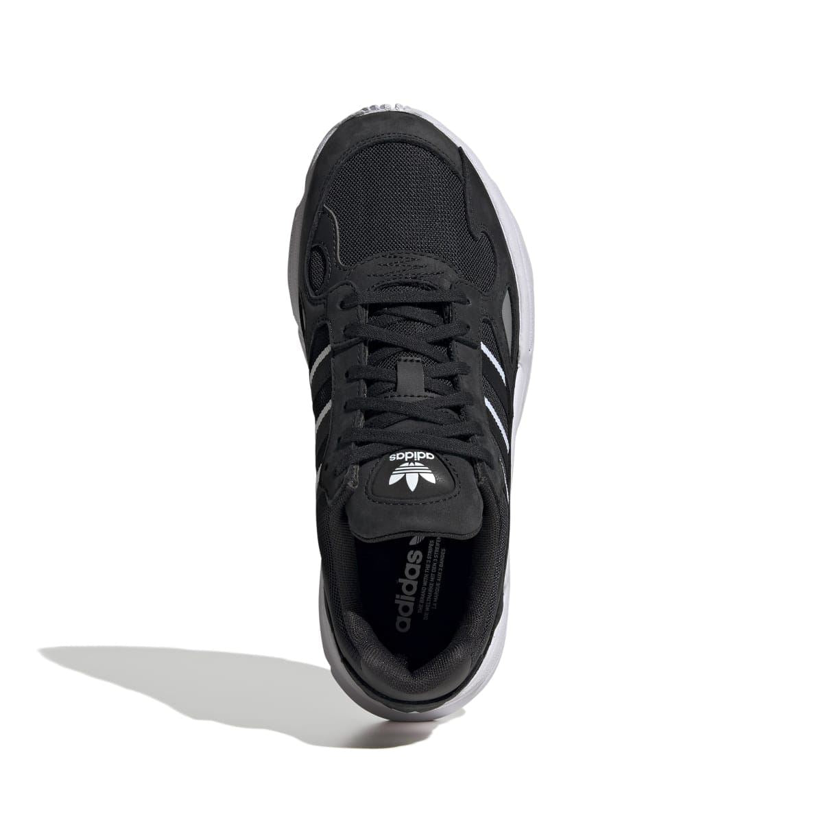 Black sneaker with lace-up front and adidas logo on tongue, view from side